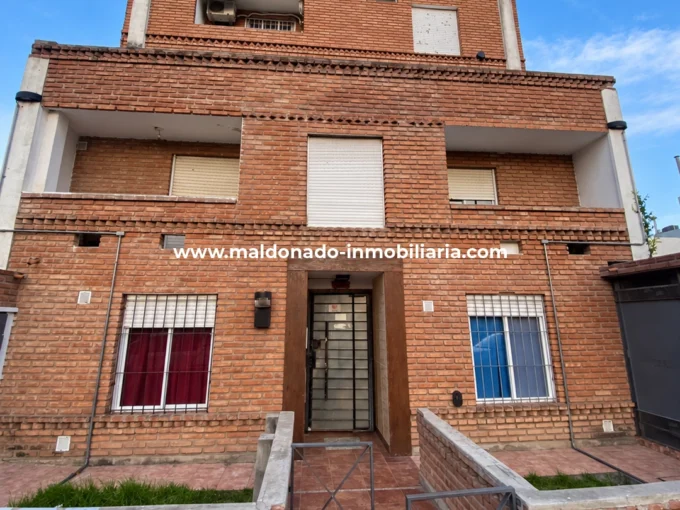 Fachada del edificio de ladrillo visto ubicado en Avenida España 430, Río Cuarto, donde se ofrece un departamento tipo dúplex en venta.